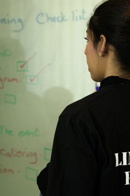 A team member reviews an event planning checklist on a whiteboard